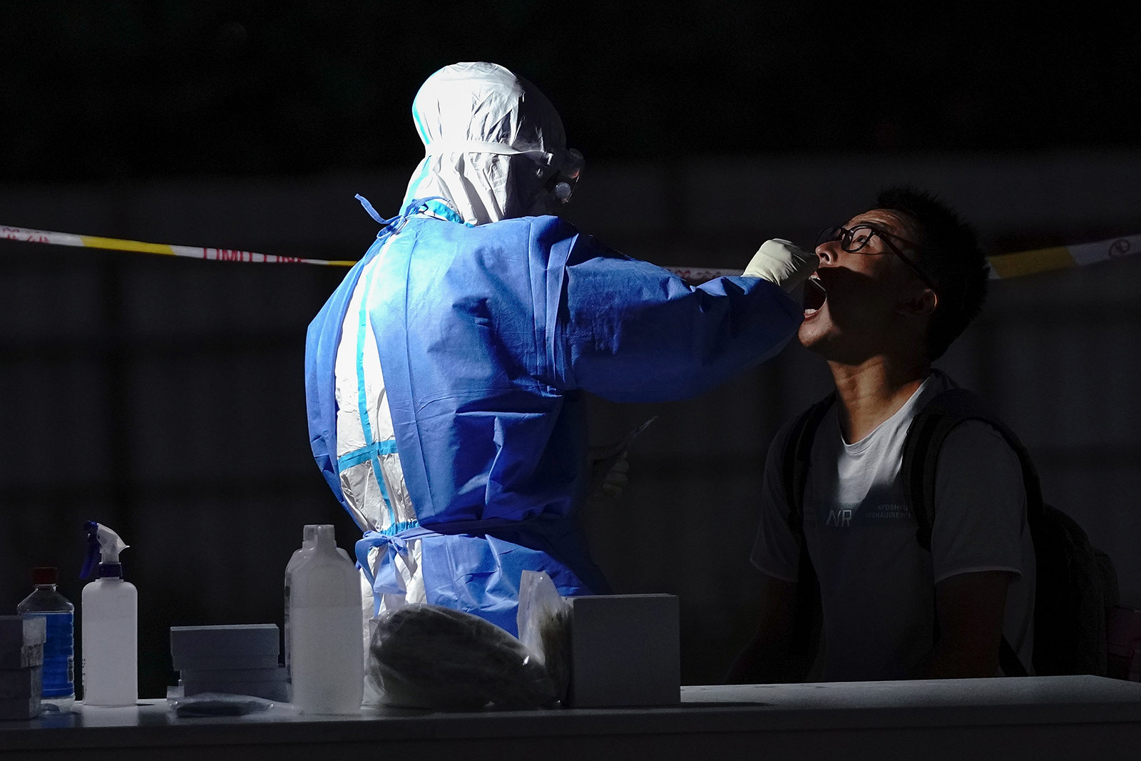 A medical worker wearing a protective suit takes a swab at a temporary test station on July 6, in Beijing.