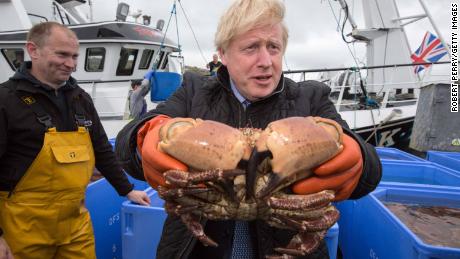 El primer ministro británico, Boris Johnson, sostiene un cangrejo en Stromness Harbour, Orkney.